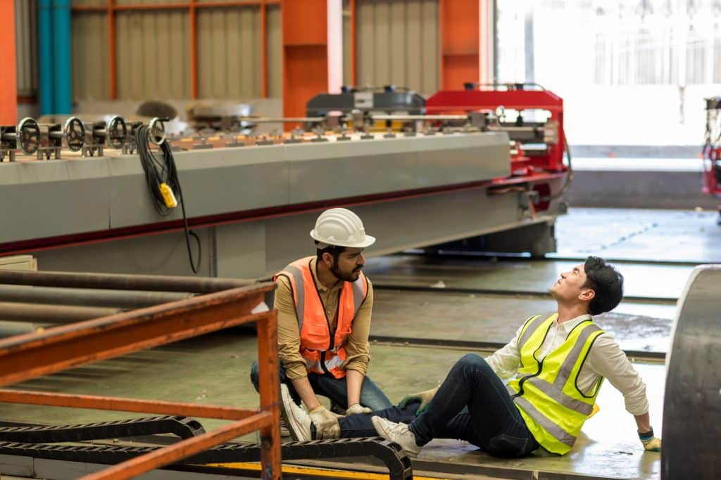 Un travailleur aidant un autre travailleur après un accident du travail en lui donnant les premiers soins.